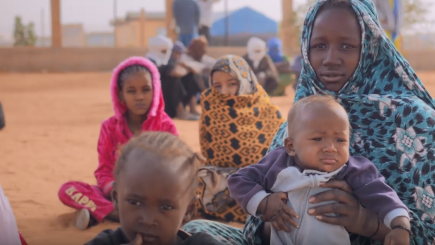 A woman and children seating in the ground.