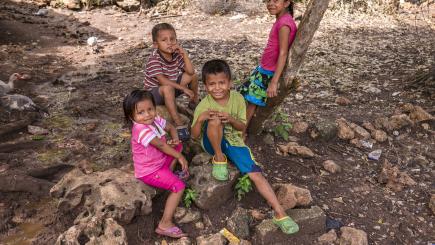 Four children play outside and smile for the camera.