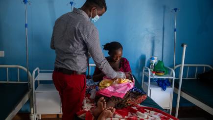 A healthworker attends to a woman and newborn baby 