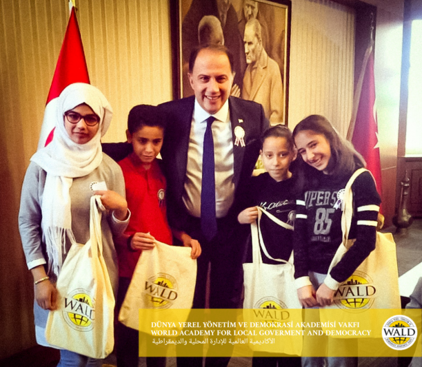 4 girls and a man smiling looking at the camera holding bags.