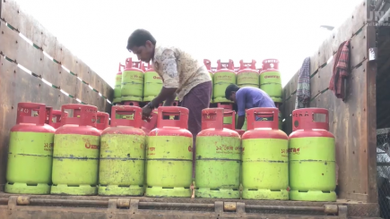 Man in middle of gas containers on top of a truck.