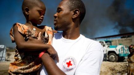 Humanitarian worker with refugee child on his arm