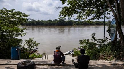 Man sits back to the camera, he is facing water