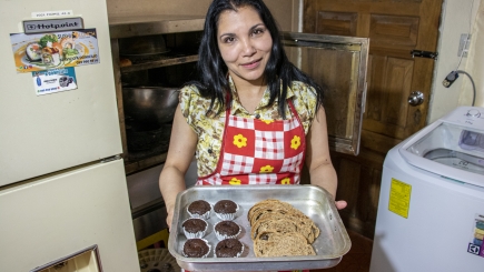 A lady shows a tray of baked goods