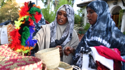 Two ladies look at goods on a market stall