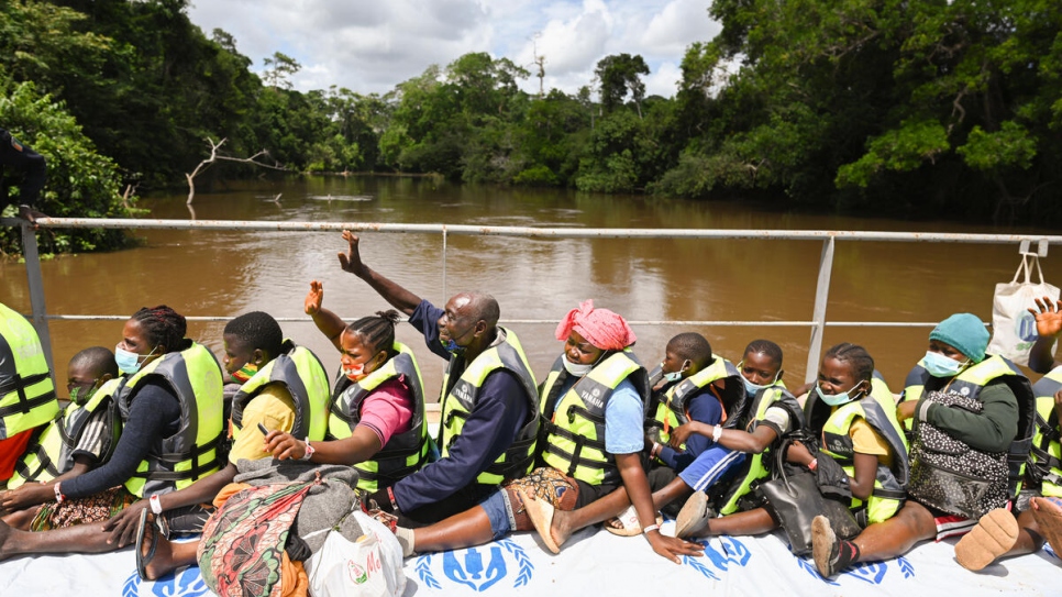 Ivorian refugees wave to waiting friends and family from the barge carrying them from Liberia back to Côte d'Ivoire.