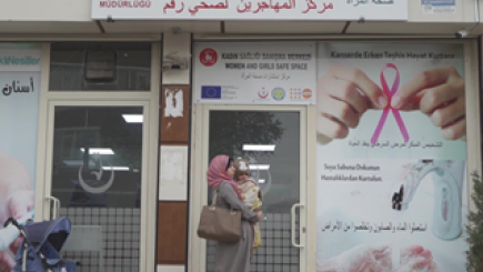 Woman walking past a Sexual and reproductive health centre with a baby. 