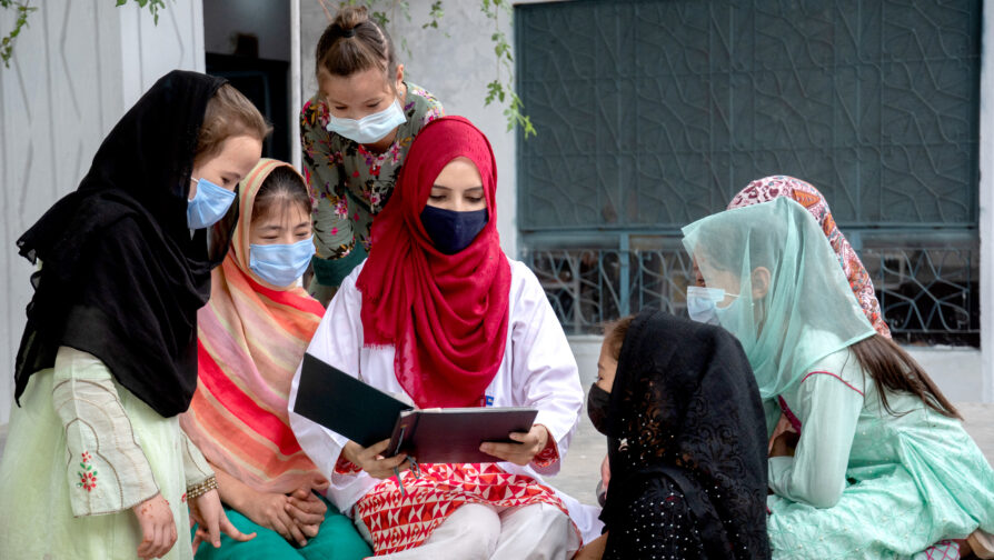 Saleema bladert door een oud fotoalbum en beschrijft haar levensreis aan jonge vluchtelingenmeisjes. ©UNHCR/Amsal Naeem