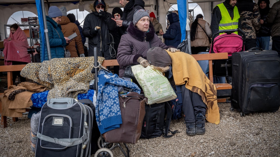 Des réfugiés bravent des températures glaciales alors qu'ils se préparent à embarquer à bord de bus au poste frontière de Palanca en Moldavie.