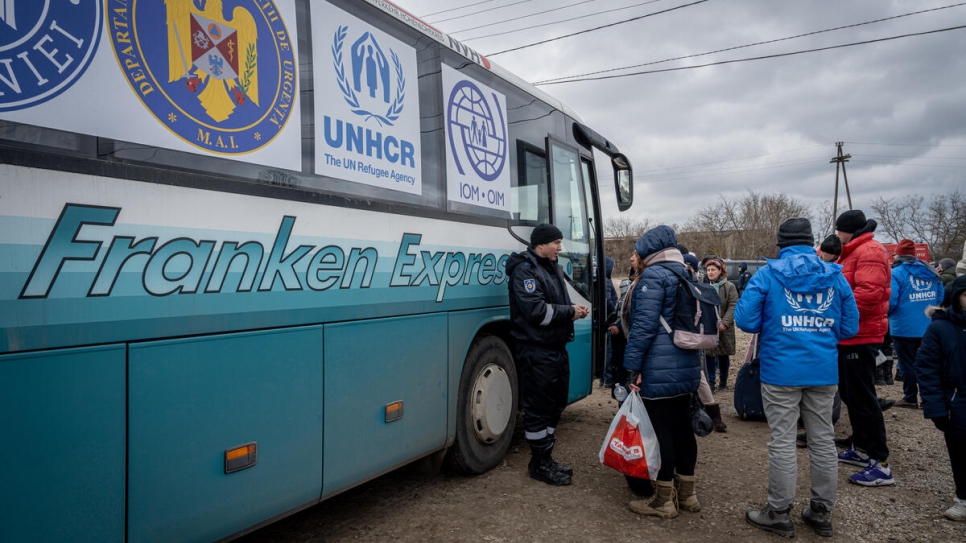 Des réfugiés prennent place à bord de bus au poste frontière de Palanca en Moldavie pour être transférés en Roumanie. 