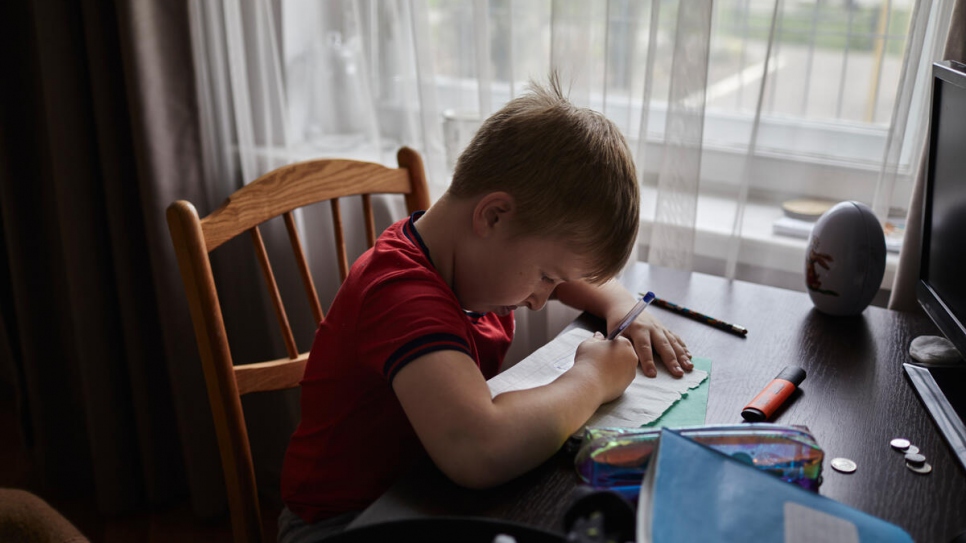 Sergey, 7, draws at a desk in the family's apartment, where he attends online classes with his school back in Ukraine.