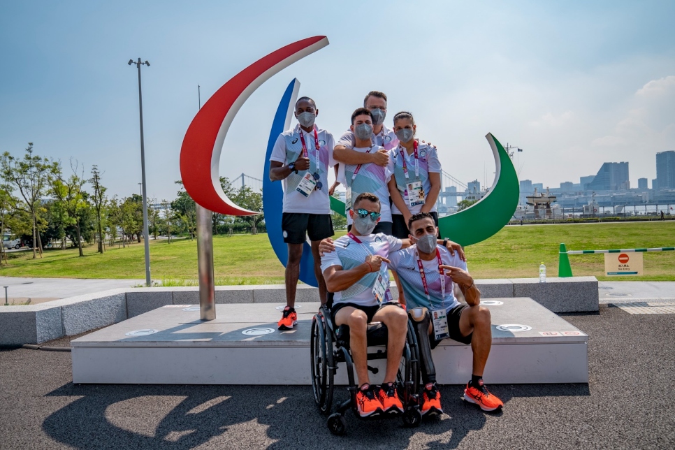 Les six membres de l'équipe paralympique des réfugiés du Comité international paralympique (CIP) se rassemblent devant le symbole des « Trois Agitos » à Tokyo, au Japon.   