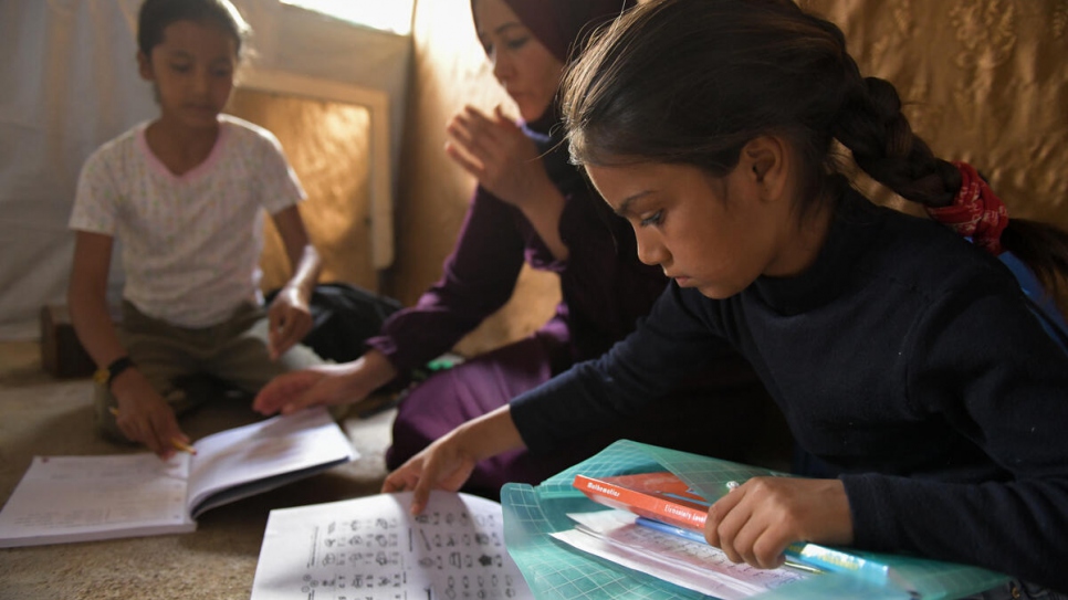 Las hijas de Majida, Sara (a la derecha) y Aya (a la izquierda), hacen sus tareas en el alojamiento de la familia.