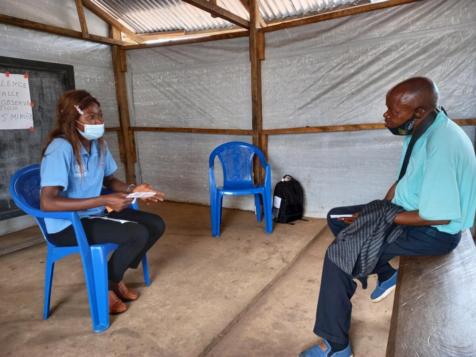 Alphonsine Mayamba conversa con un refugiado que fue vacunado recientemente en el asentamiento de Lóvua, Angola.