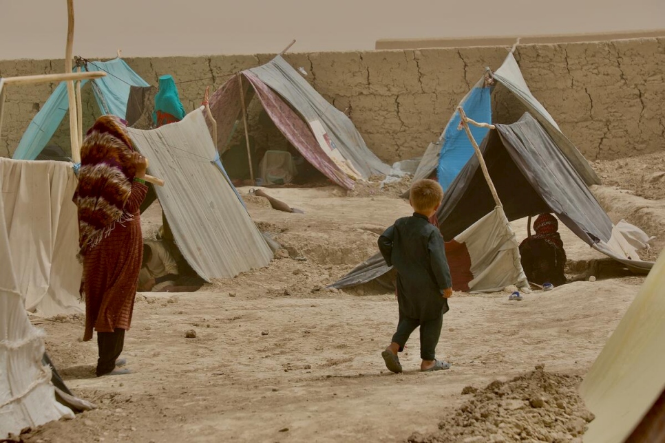 Une femme et un enfant marchent entre les tentes de fortune du camp de déplacés internes de Nawabad Farabi-ha, à Mazar-e Sharif, dans le nord de l'Afghanistan.  