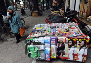 A Vietnamese woman walks past a newsstand in downtown Hanoi, Jan. 11, 2013.