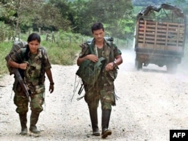 Two members of the rebel Revolutionary Armed Forces of Columbia (FARC) trek toward Los Pozos in Colombia (file photo)