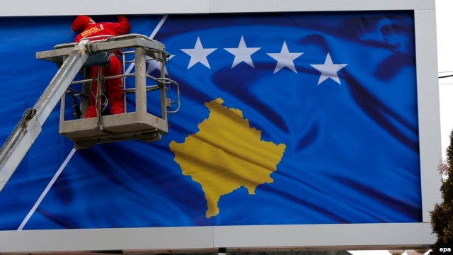 A worker fixes the national flag of Kosovo to a billboard ahead of Kosovo's fifth anniversary of its independence in Pristina in February 2013.