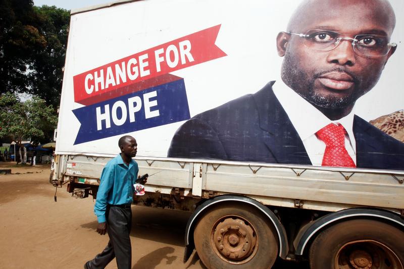 A supporter walks by an image of George Weah, President of Liberia, in Monrovia, Liberia, December 27, 2017. 