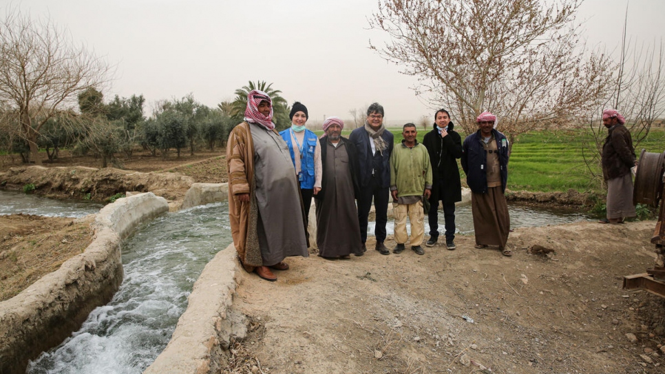 Agricultores de la aldea de Al-Keshmah observan cómo el agua de una estación de riego reparada empieza a fluir por los canales de concreto hacia sus tierras en Deir ez-Zor, al este de Siria.