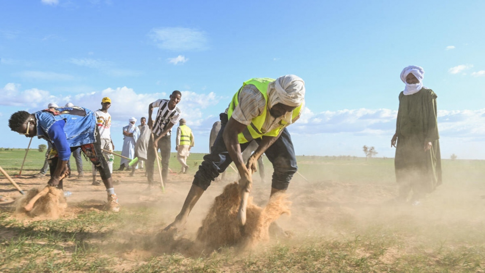 Ahmedou Ag Albohary y otros voluntarios practican el uso de ramas para apagar incendios forestales ficticios durante una sesión de capacitación cerca del campamento.