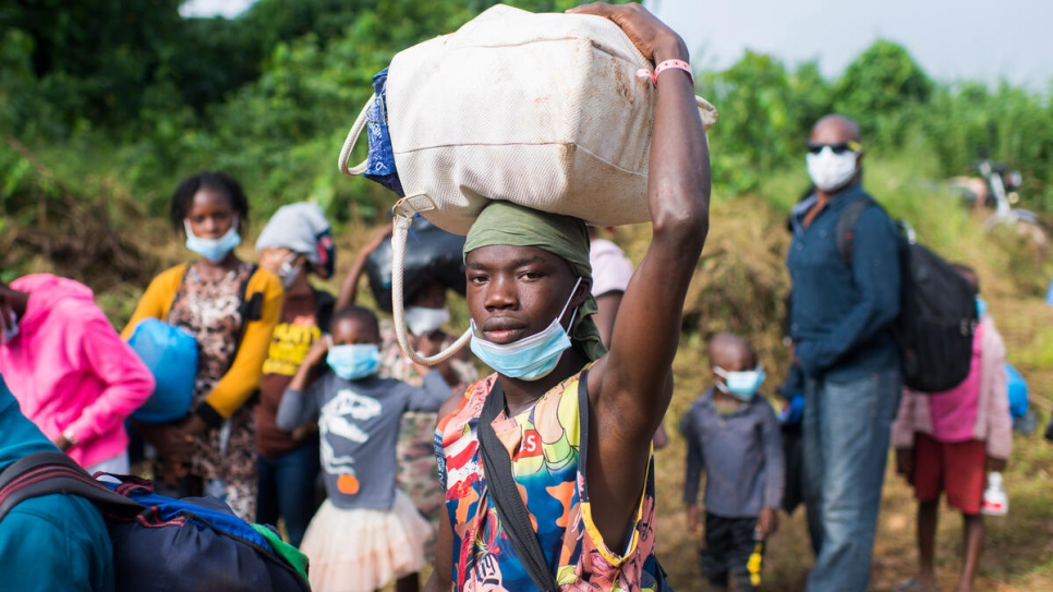 Tagan Gomet y otras personas de Côte d'Ivoire llevan sus pertenencias a la barcaza que las llevará de vuelta a su país.