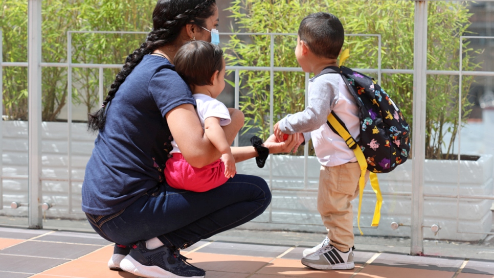 Marsely y sus hijos Santiago (3) y Damaris (1) juegan en la terraza de un albergue en Bogotá, antes de participar en actividades de formación técnica y pedagógicas que apoyan su integración socioeconómica en Colombia.