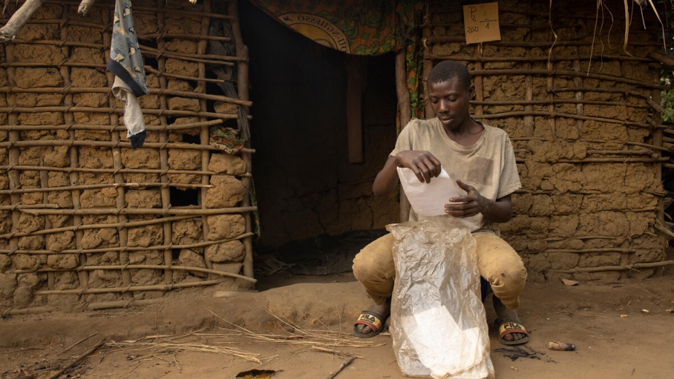 Mawaki Ngandibi comprueba los documentos de identidad de su familia antes de meterlos en una bolsa de plástico para protegerlos de la intemperie. 