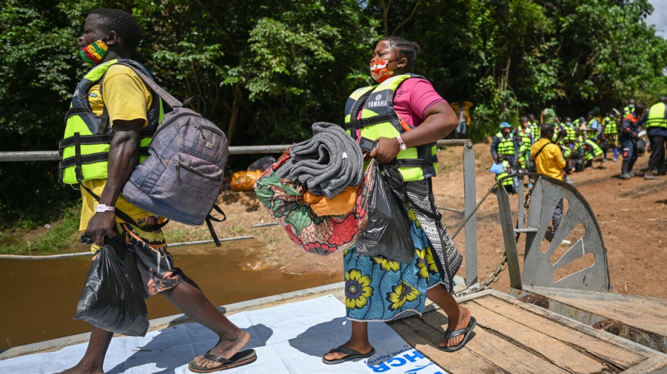 Personas retornadas de Côte d'Ivoire abordan la barcaza para cruzar el Río de Cestos, que delimita la frontera entre Liberia y Cote d'Ivoire.