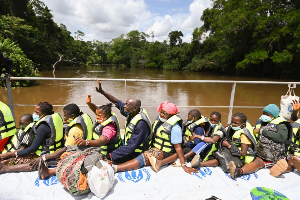 Desde la barcaza, estas personas saludan a amistades y familiares que aguardan en la orilla del río para darles la bienvenida.