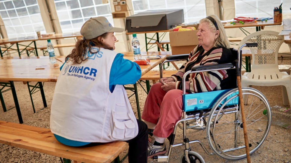 An emotional Svetlana, 83, is comforted by UNHCR partner staff at a rest area in Palanca, Moldova.