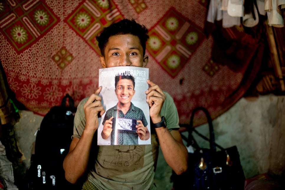 Hasson holds up the Rohingyatographer magazine which features him on the cover.