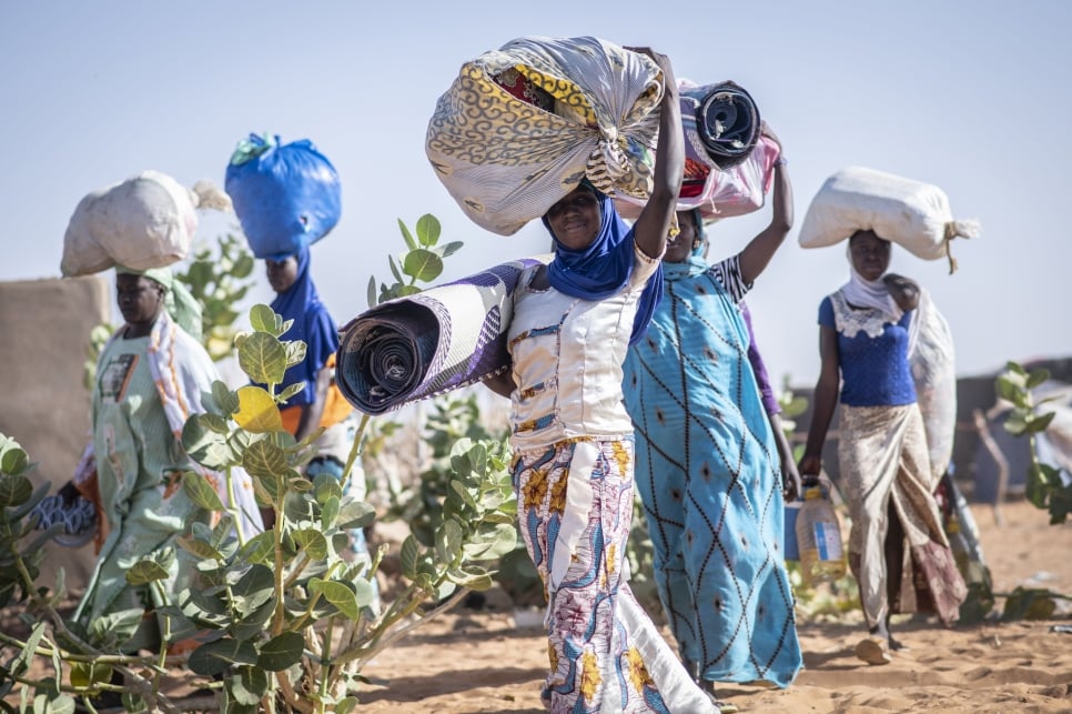 Malian refugee women carrying their belongings through Mbera refugee camp in Mali. Mbera camp in south-east Mauritania is home to nearly 60,000 Malian refugees.