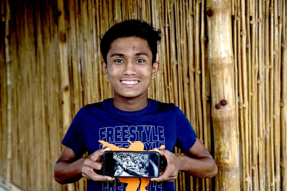 Hasson holds a mobile phone showing the photograph of him taken by Kevin Frayer in 2017, soon after he arrived to Bangladesh with his family. 