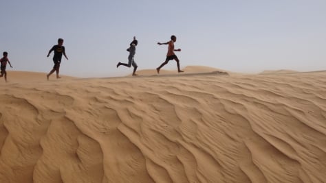 Young children from the Sahrawi community play on the sand dunes at Dakhla camp in Tindouf, western Algeria, close to the border with Morocco and Western Sahara.