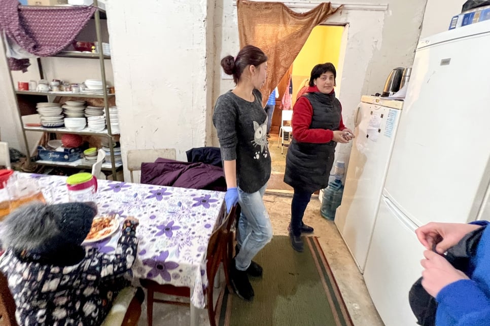 Rymma and a volunteer help organize a meal in the hostel's communal dining room.