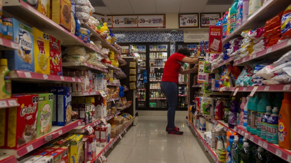 A Salvadoran refugee stacks shelves at a convenience store in Monterrey, Mexico, where she works as a shift supervisor.