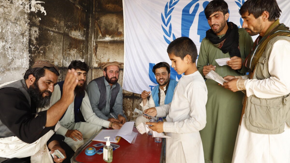 A family displaced to Kabul receive cash to help them return to their province.