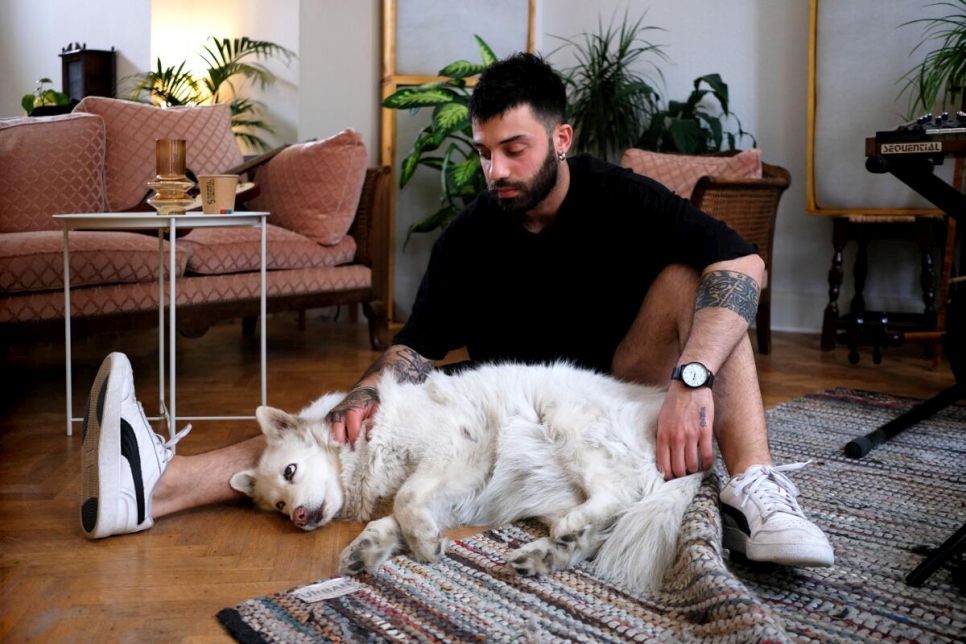Belgium. Syrian refugee and musician Bassel cuddles his white shepherd dog Stella in their new home