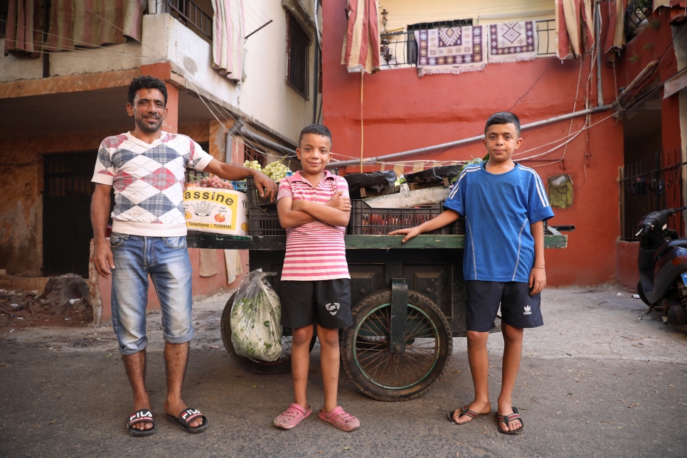 Syrian refugee, Gaith (in blue), 13, stands beside his father's fruit and vegetable cart in Beirut with his dad Samer Mohammed Ameno, 42, and brother Mohammed, 12. Gaith dreams of becoming a famous footballer and is ecstatic about moving to the city of his dream club, Real Madrid.