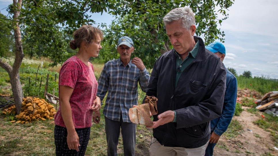 Le Haut Commissaire Filippo Grandi tient un morceau du missile qui a détruit la maison de la famille. 