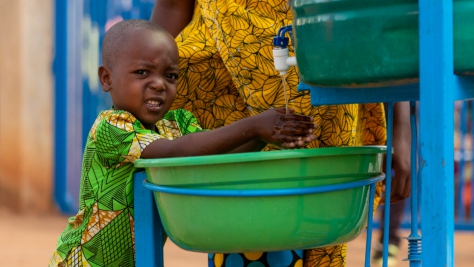 A young Burundian refugee washes his hands before boarding a bus with his family to voluntarily return home after living in exile since 2015.