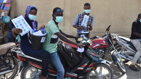 Wearing protective masks, Idriss, 21, and Leila, 25, both refugees from the Central African Republic, travel through N'Djamena, Chad distributing materials to raise awareness about COVID-19.