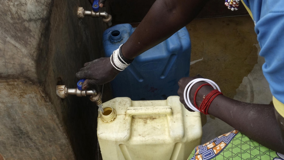 Women from the local Ugandan community fill jerrycans from the water distribution point set up to serve refugees together with local communities around Bidibidi refugee camp.