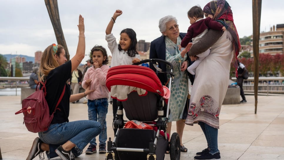 Volunteers Karmele Villarroel Labanda (kneeling) and Begoña Herrero entertain the family on a day trip to the Guggenheim Museum in Bilbao.