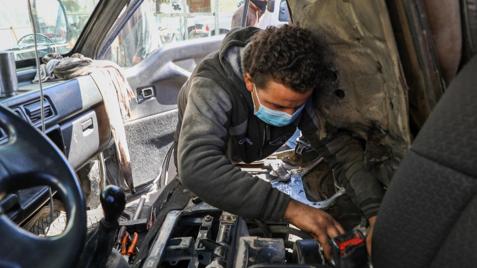 Syrian refugee Khalil, 18, repairs a vehicle at the garage in Amman where he works for US$10 each day.