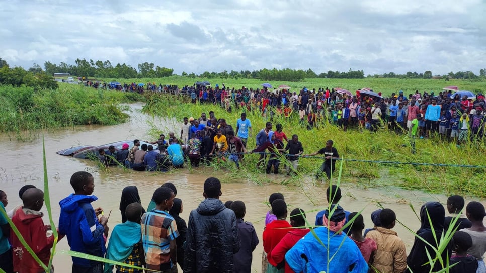 Residents of Nkando village try to remove a vehicle that was washed away when Chikuli river burst its banks during Tropical Storm Ana.