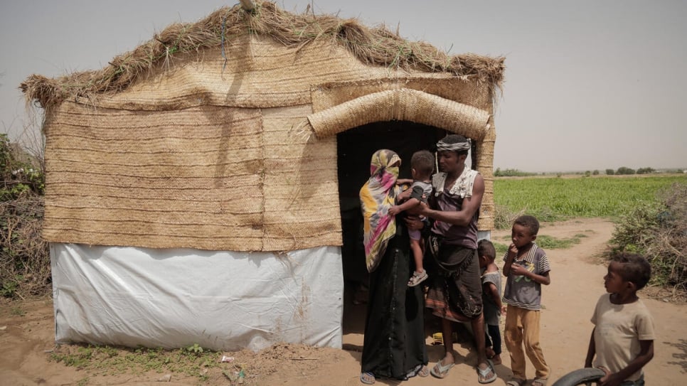 An internally displaced family stand outside a shelter provided by Jeel Albena at a hosting site in Hudaydah, Yemen.