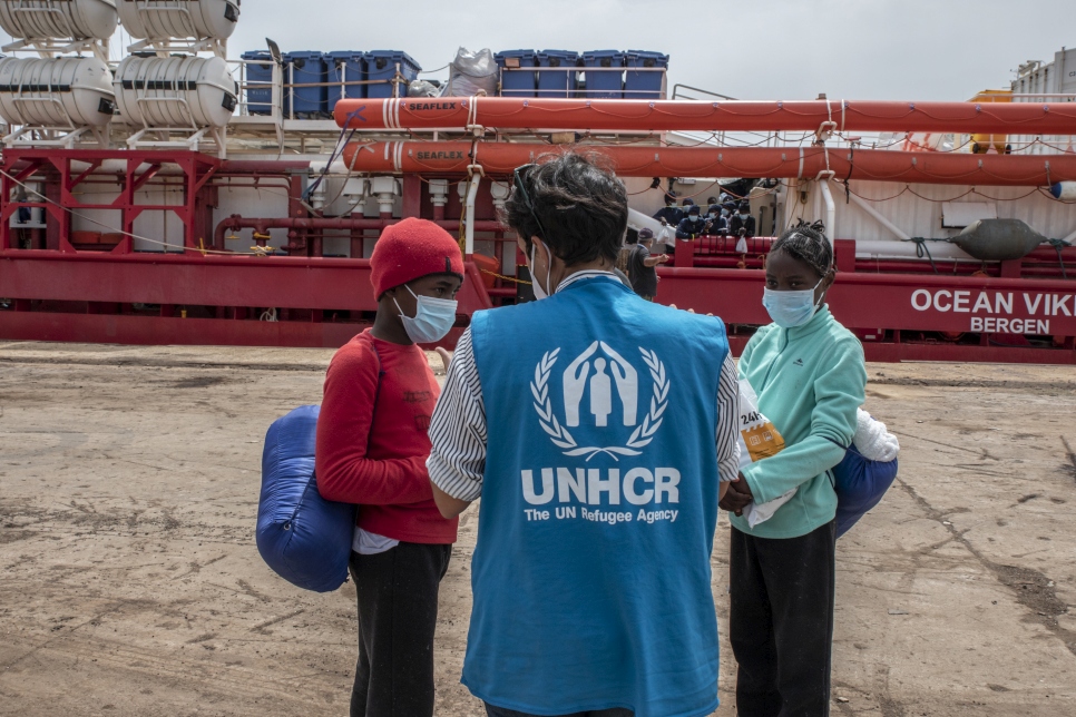 Un employé du HCR s'entretient avec des réfugiés et des migrants qui viennent de débarquer au port d'Augusta, en Sicile, le 1er mai 2021.  