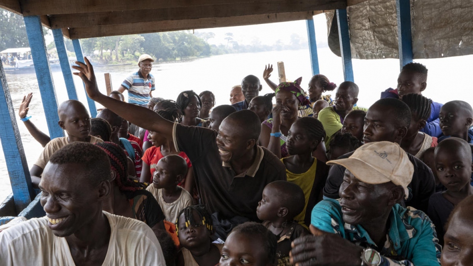 Des réfugiés centrafricains saluent de la main alors que le bateau qui les transporte vers leur pays d'origine quitte Zongo en République démocratique du Congo. Novembre 2019. 